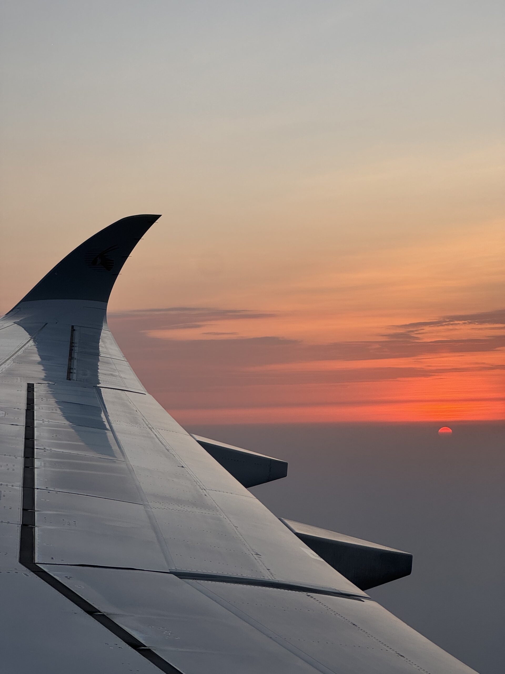 Airplane wing with sunset sky and clouds in the background